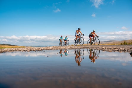 Cyclists pass a large puddle on a sunny day