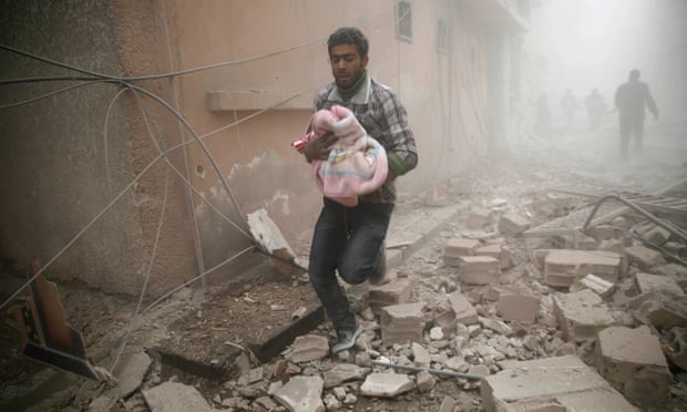 A Syrian man carries a baby wrapped in a blanket following airstrikes on the town of Douma, a rebel stronghold east of Damascus