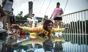 A visitor poses for a photograph on the world’s highest and longest glass-bottomed bridge above a valley in Zhangjiajie in Hunan province.
