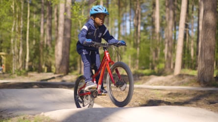 A boy on a bike cycles through woodland