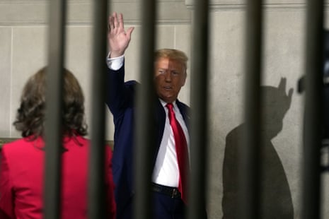 Donald Trump waving from behind a row of vertical bars.
