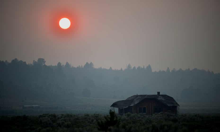 Thick smoke causes the sun to glow red over an abandoned farmhouse as the Bootleg fire expands near Beatty, Oregon.