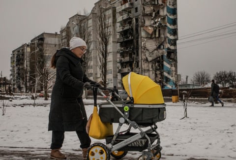 A woman pushes a stroller in the snow-covered streets of Borodianka, north of Kyiv.