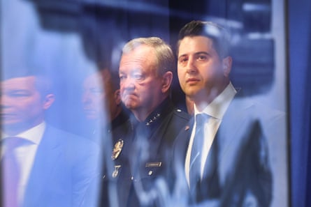 Men standing together, with their images reflected in glass over a handgun.