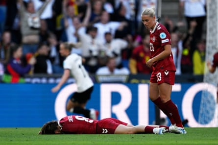 Emma Snerle lies on the turf after being clattered by a clearance, while Germany’s celebrations begin in the background