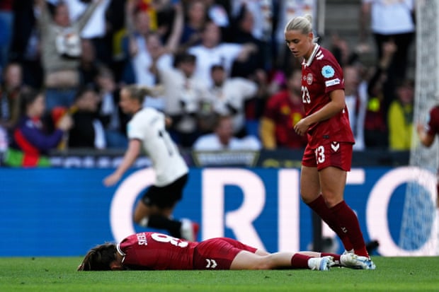 Emma Snerle lies on the turf after being clattered by a clearance, while Germany’s celebrations begin in the background. Photograph: Matthias Hangst/Getty Images