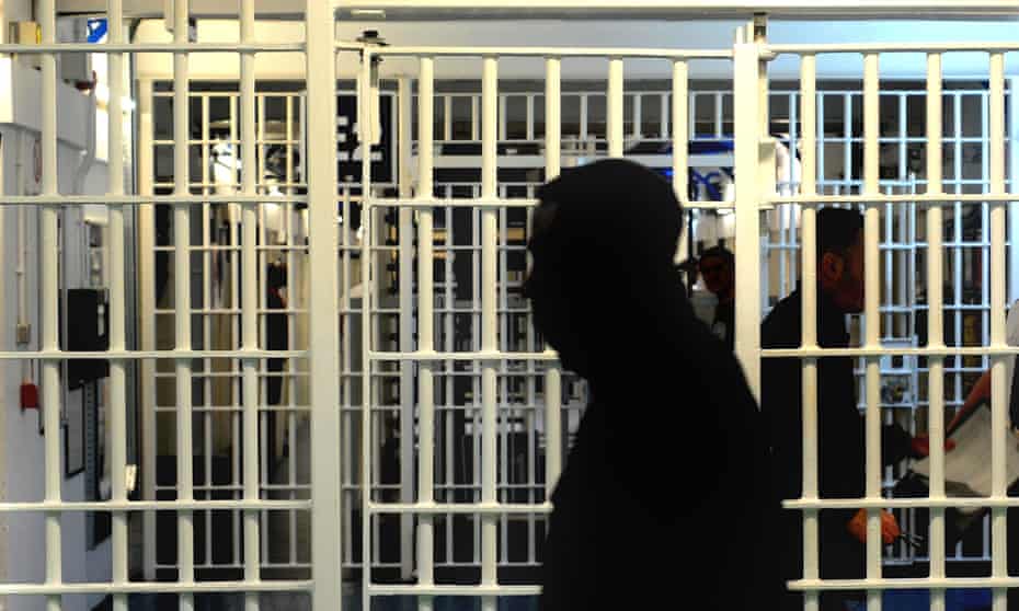 Silhouette of a man walking past a prison cell