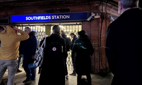 Passengers stand outside locked gates at the entrance to Southfields underground station in south London.