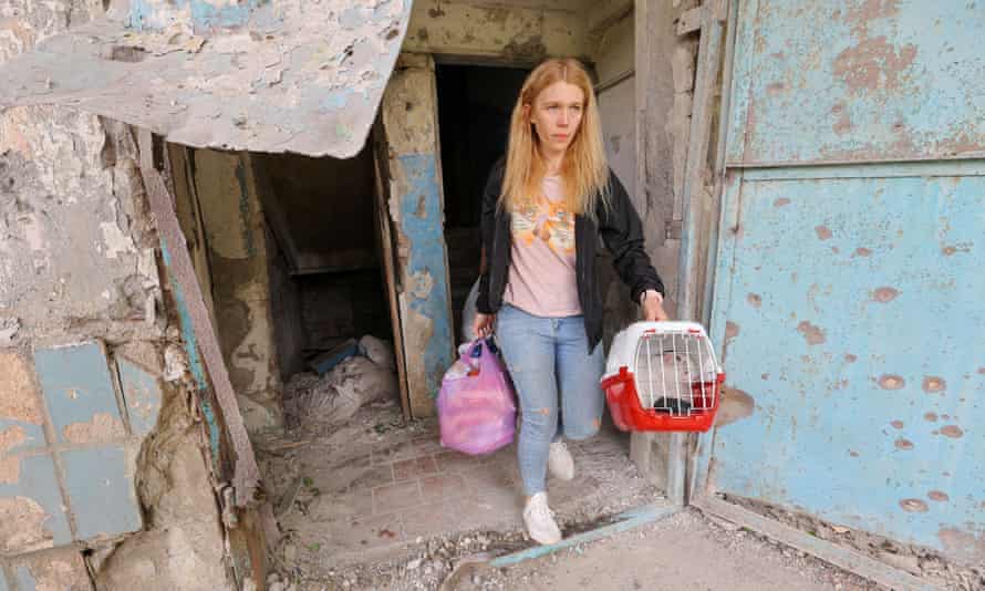 Una mujer lleva sus pertenencias y un gato al salir de una casa dañada tras los recientes bombardeos en el distrito de Petrovsky de Donetsk.