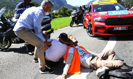 A Tour de France official attempts to drag two protestors off the road during Tuesday’s stage.