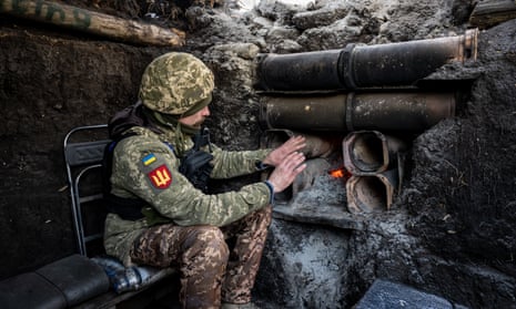 A Ukrainian soldier warms himself beside a fire in a dugout bunker in the southern Donbas region, Ukraine.