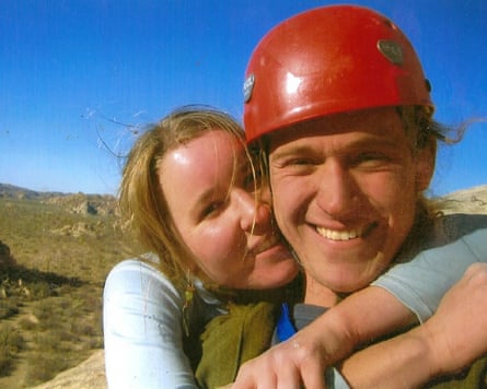 a woman hugs a man wearing a climbing helmet as they stand in nature