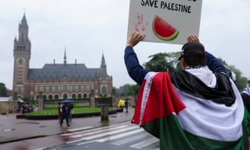 A protester draped in a Palestinian flag holds up a sign at a protest in support of Palestinians in Gaza