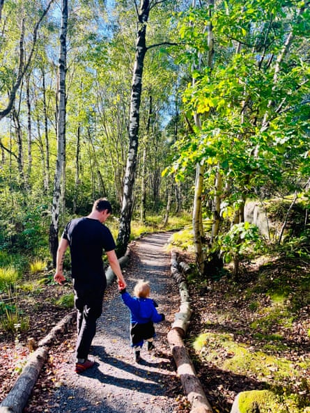 Simon Montgomery holds his toddler’s hand walking along a wooded path