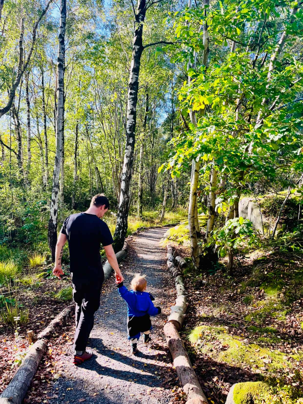 Simon Montgomery holds his toddler’s hand walking along a wooded path