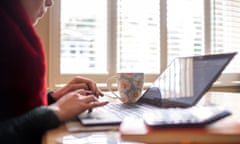 A woman sits at a table working on her laptop