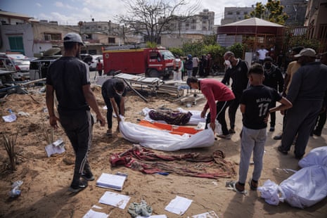 This photograph, taken yesterday, shows Palestinians preparing a body for reburial after it was removed from the mass grave in the yard of Nasser hospital.