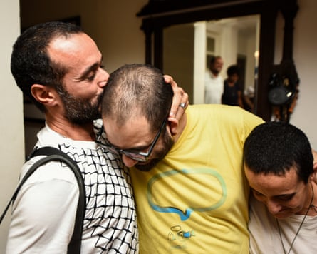A man kisses Alaa Abd el-Fattah on his head as another hugs him