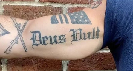 a tattoo of the words ‘Deus Vult’ on a man’s bicep