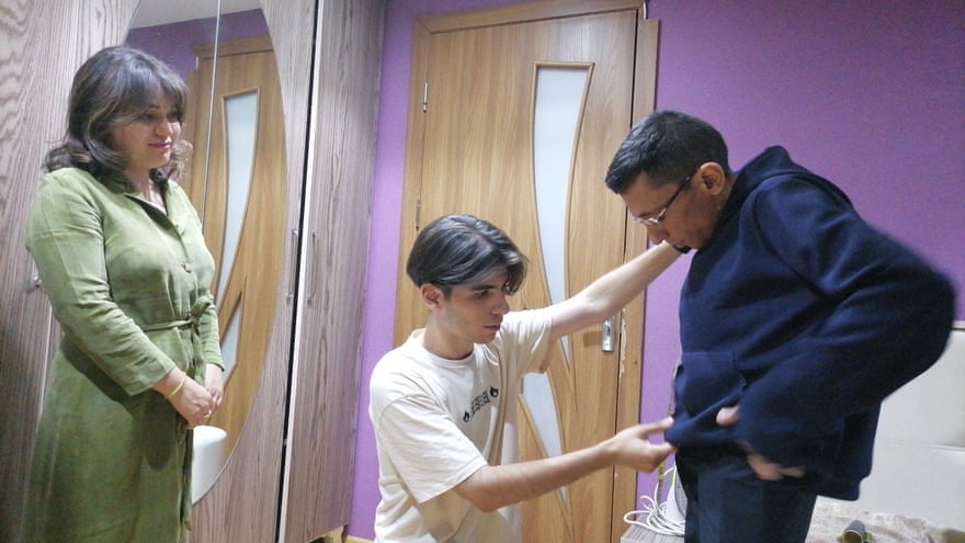 Mahammad Kekalov helps Rahim Rzayev try on a hoodie designed for people with disabilities by designer Rashada Aliyeva.