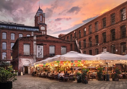 Renovated red-brick mills for a backdrop to outdoor tables were diners eat and drink beneath colourful lights.