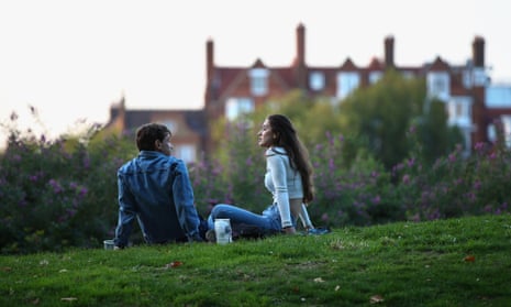 Young man and woman sit on grass in city park