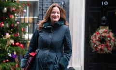 Gillian Keegan outside 10 Downing Street – she is wearing a black coat with fluffy collar and holding a red folder, walking away from No 10's door, which has a Christmas wreath; there is a decorated Christmas tree behind her