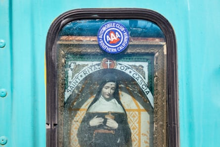 An image of a Christian saint and a sticker for AAA on the back of a blue bus
