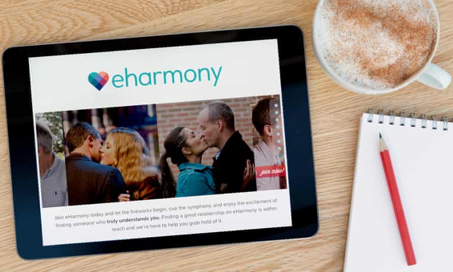 The eharmony website on an iPad on a wooden table beside a notepad.