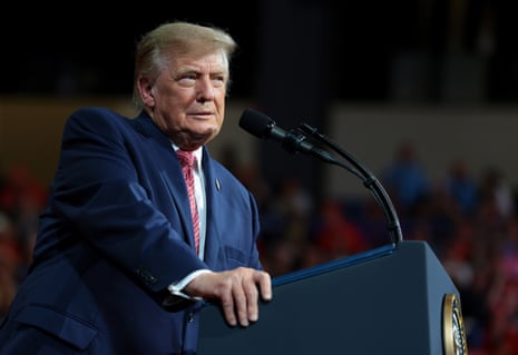 Donald Trump speaks into a microphone at a podium during a campaign rally
