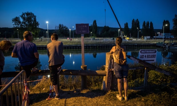 Diváci a miestni obyvatelia sa pozerajú na tím záchranárov, ktorí prevážajú nezvestnú veľrybu belugu uväznenú v Seine.