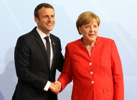 Macron and Merkel shaking hands and smiling