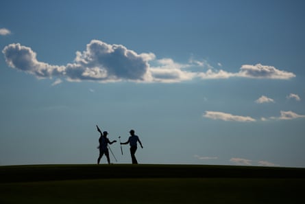 Wyndham Clark hands a club to his caddie on the 10th hole