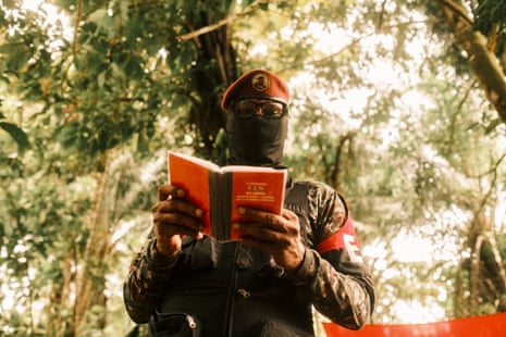 Commander Yerson reads from a small red book standing in a jungle clearing