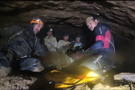Rescuers sit at the entrance to the cave.