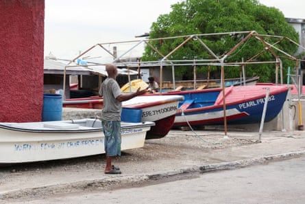 A man standing next to fishing boats on land