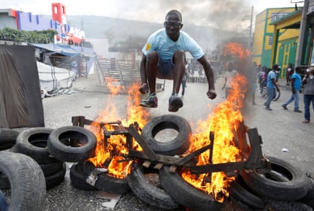 A protester hurdles a burning barricade during a protest in Port-au-Prince, the Haitian capital