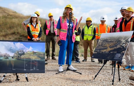a woman in a reflective vest and a hardhat speaks