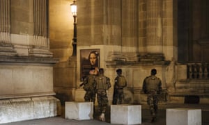 Military patrol near the Louvre museum during curfew in Paris Saturday night. The monthlong curfew came into effect Friday at midnight, and France is deploying 12,000 extra police to enforce it.