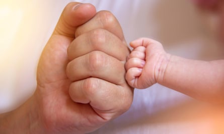 Parent Holding in the Hands baby Hand clenched into fist of Newborn Baby.