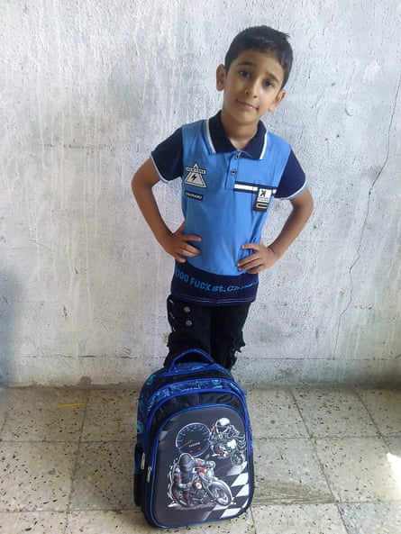 Karam al-Ghussain standing for a photo with a children’s backpack