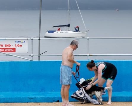 Two people and a dog next to the pool