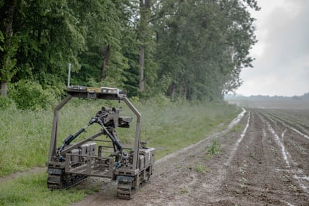 A small military drone vehicle with a machine gun tripod on top, in a muddy field