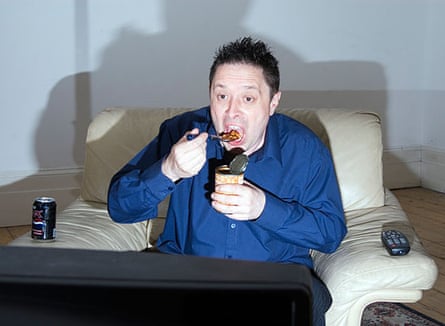 Single man eating tin of beans in front of television England UK
