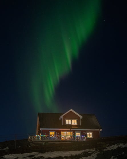 Green lights in sky above two-storey house with lights on