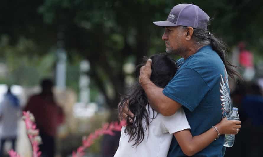 A man hugs a girl outside a school.