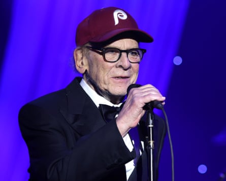 Art Garfunkel onstage wearing cap and holding mic