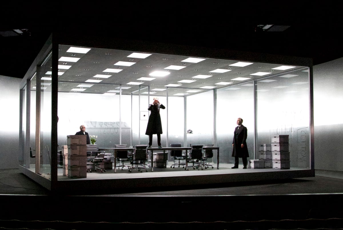 A large, glass box containing men, tables a boardroom table and boxes