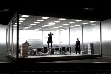 A large, glass box containing men, tables a boardroom table and boxes