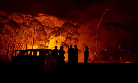 Residents look on as flames burn through bush in Lake Tabourie, New South Wales.